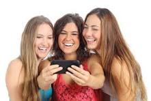 Three young women laughing at something on a phone. Image provided by Peter Drake a science teacher at QEHS Hexham Northumberland